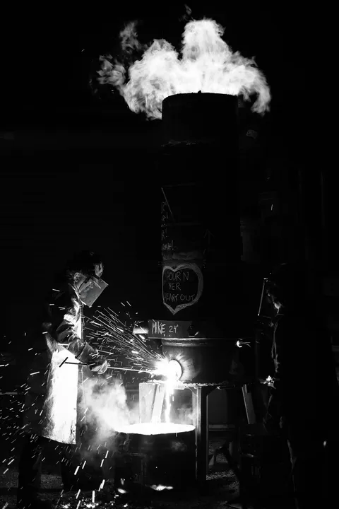 Forgeron façonnant le fer au marteau, de nuit