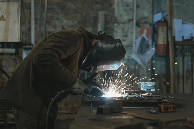 Artisan soudant une pièce métallique en atelier